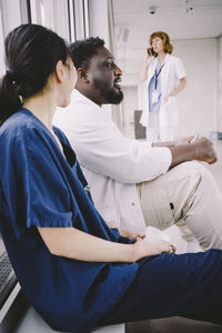 Side view of male and female medical colleagues sitting at hospital cafeteria