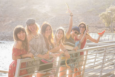 Women holding watermelon while standing by railing