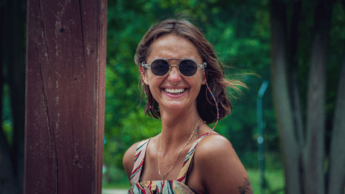 Portrait of smiling woman wearing sunglasses standing outdoors