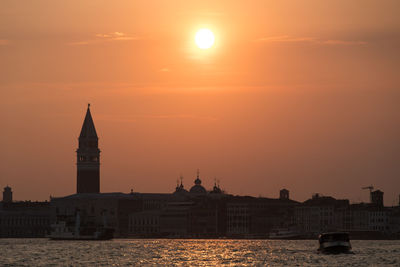 Boat sailing on grand canal by church of san giorgio maggiore against sky during sunset
