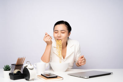 Young woman using laptop on table against white background