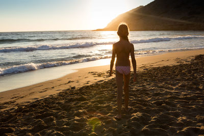 Rear view of woman standing on beach