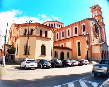 Cars on street by buildings in city against sky