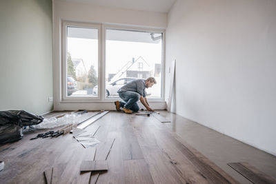 Mature man fitting flooring in new home