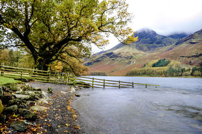 Bridge over river by tree mountains against sky