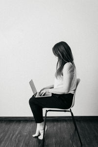 Side view of young woman sitting on chair