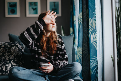 Woman sitting on sofa, not willing to be photographed