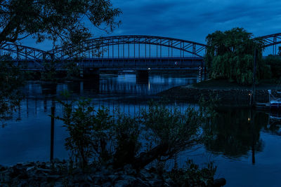 Arch bridge over river against sky at dusk