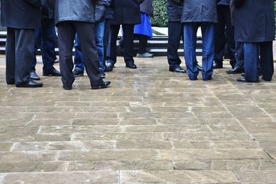 Low section of people standing on cobblestone