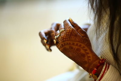 Midsection of woman with henna tattoo against blurred background