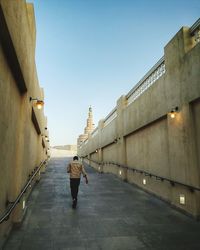 Rear view of man walking on footpath at souq waqif