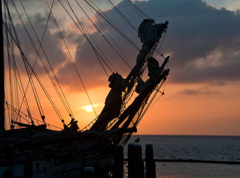 Silhouette sailboat by sea against sky during sunset