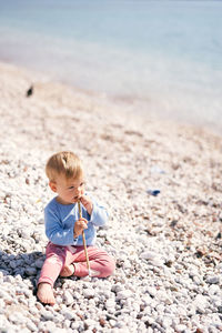 Boy sitting on pebbles at beach