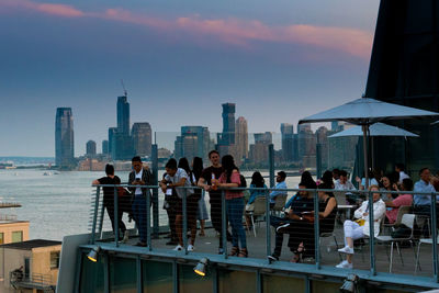 People on modern buildings in city against sky