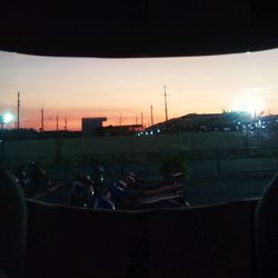 People in illuminated city against sky during sunset