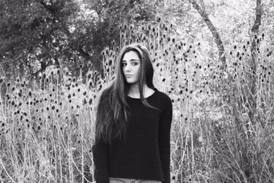 Portrait of young woman standing against plants