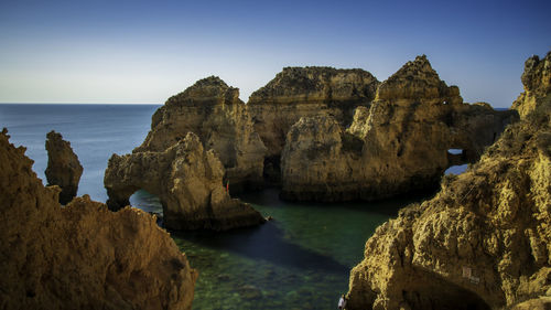 Panoramic view of rocks on beach against clear sky