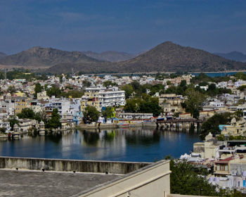 Town by lake and mountains against sky