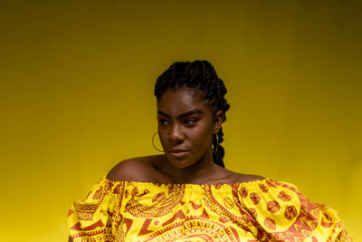 Young woman wearing colorful long clothes over yellow background. natural expression.