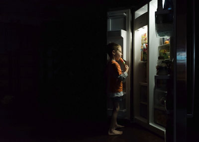 Side view of boy looking at entrance to at night