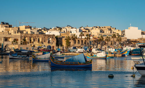 Sailboats moored at harbor against buildings in city