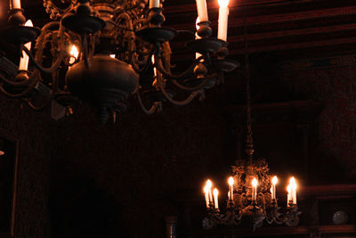 Old glowing chandeliers lanterns illuminated hanging from ceiling inside castle