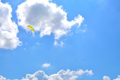 Low angle view of paragliding against blue sky