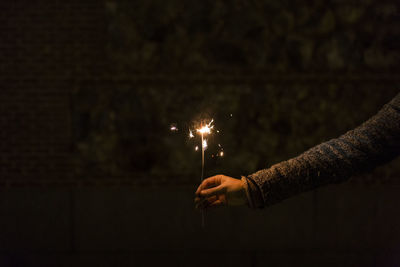Cropped hand of person holding sparkler at night