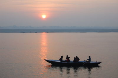 People in boat on sea against sky during sunset