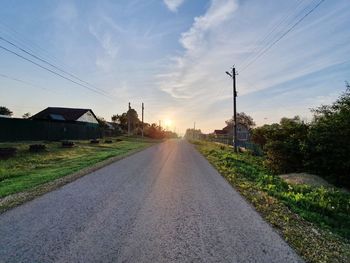 Road amidst buildings against sky during sunset