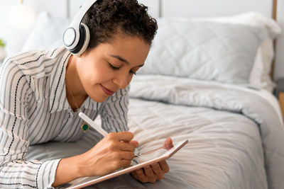 Young man using digital tablet while lying on bed at home