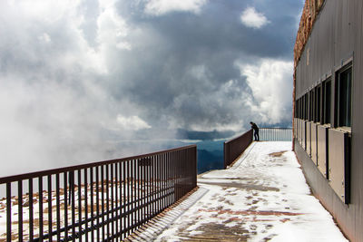 Snow covered pathway against clouds