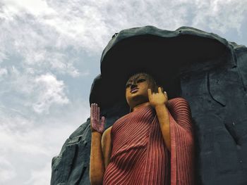 Low angle view of buddha statue against sky