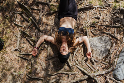 Carefree woman relaxing on land covered with roots in forest at la pedriza, madrid, spain