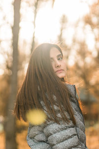 Young woman standing against trees