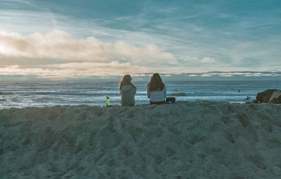 Rear view of couple sitting on beach