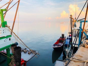 Fishing boats moored in sea against sky