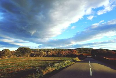 Road amidst field against sky