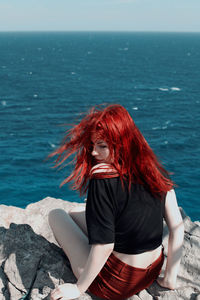 Woman with redhead sitting n rock against sea