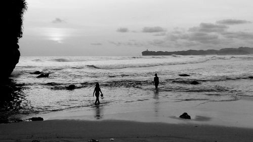 Silhouette people on beach against sky