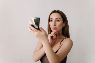 A beautiful natural woman makeup artist preens herself with makeup on a white isolated background