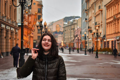 Portrait of young woman standing on city street