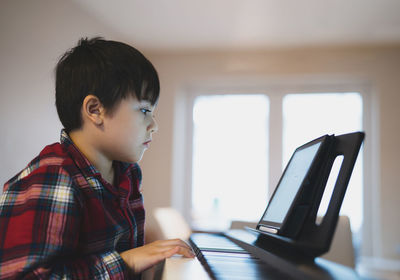Portrait of kid playing piano, young boy learning music with an electric piano 