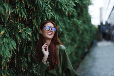 Portrait of young woman wearing sunglasses standing outdoors