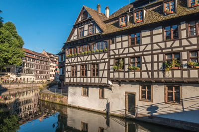 Buildings by canal against sky in city