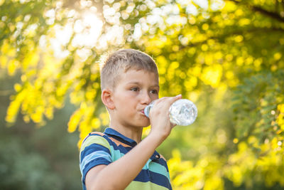 Boy drinking water while standing outdoors