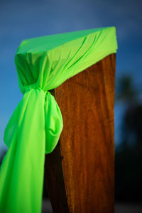 Close-up of green wooden post against blue sky