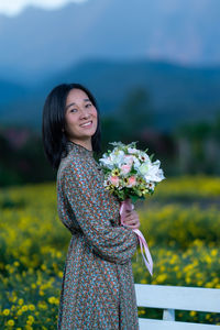 Woman standing by flower on field