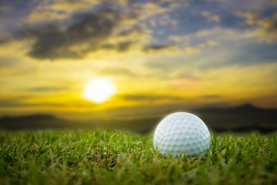 Close-up of golf ball on field against sky during sunset