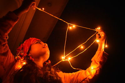 Low angle view of woman against illuminated lights